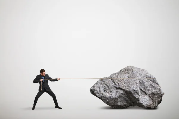 Businessman in formal wear pulling the big stone — Stock Photo, Image