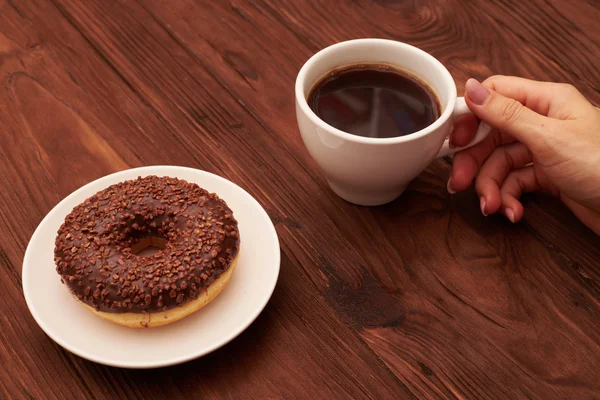 Chocolate donut and womans hand — Stock Photo, Image