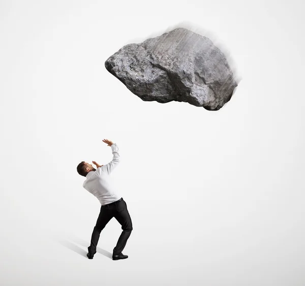 Scared businessman under big flying stone — Stock Photo, Image