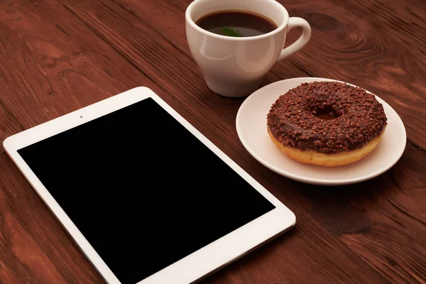 tablet pc, chocolate donut and cup of coffee
