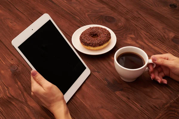 tablet pc ve kahve ahşap masa üzerinde tutan kadının el