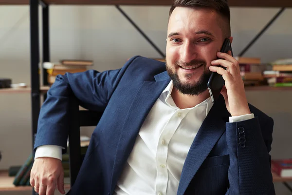 Hombre de negocios hablando por teléfono y sonriendo en la oficina — Foto de Stock