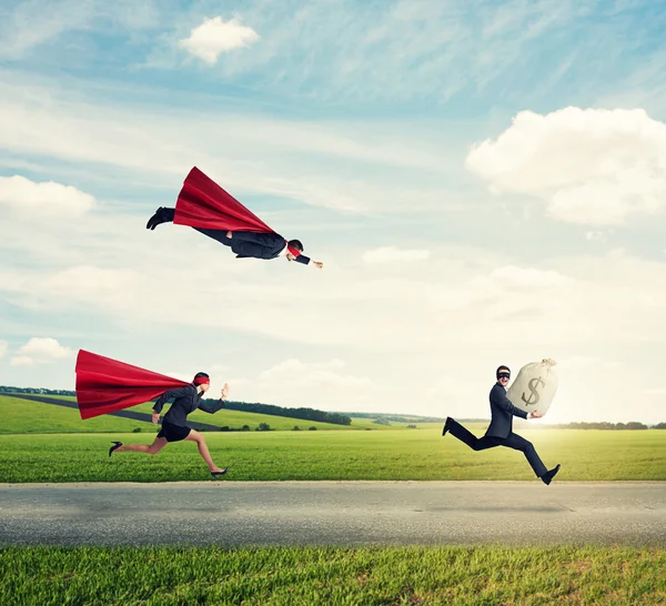 Superheroes trying to catch a thief — Stock Photo, Image