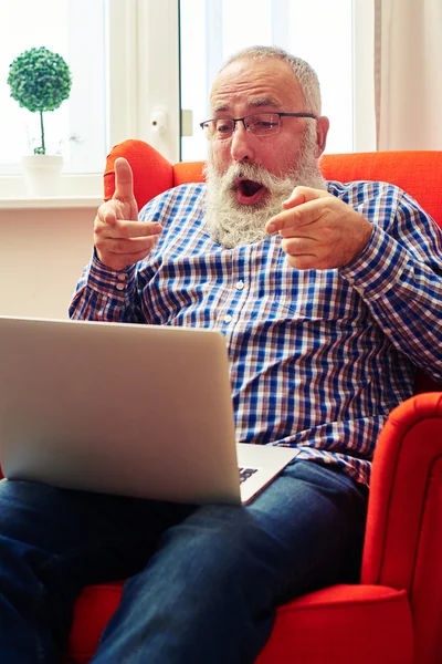 男は椅子に座って、ノート パソコンを指す — ストック写真