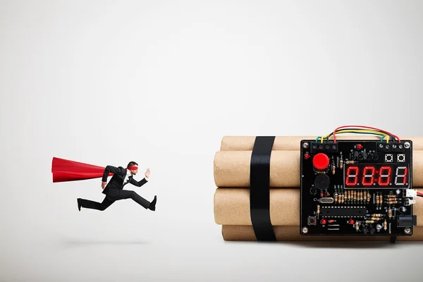 Superman i röd kappa och mask redo att desarmera stor bomb — Stockfoto
