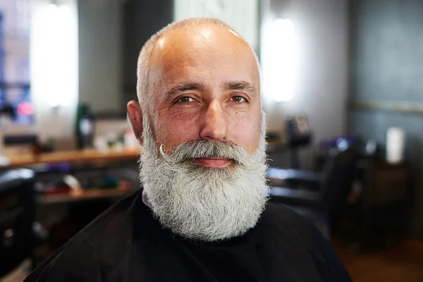 Uomo anziano sorridente con barba in negozio di barbiere — Foto Stock