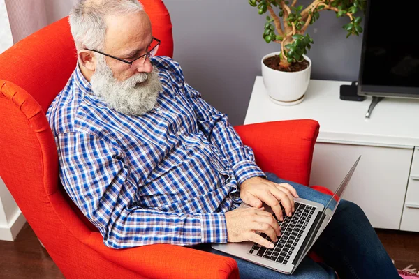 Mann mit Brille sitzt mit Laptop auf dem Stuhl — Stockfoto