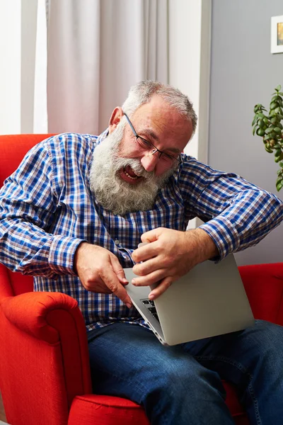 Homem sentado na cadeira vermelha e quebrando seu laptop — Fotografia de Stock