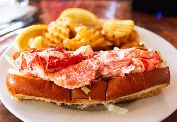 A fresh lobster roll served with waffle fries in a restaurant in Portland Maine.