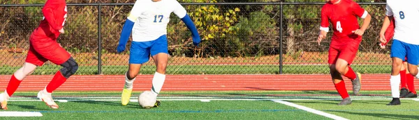 緑の芝生のフィールドでサッカーの試合中にボールを制御する高校生の男の子 — ストック写真