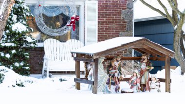 Noel için bir mesken evi, penceresinde beyaz bir tel çelenk ve kar fırtınasından sonra gün ışığında ön bahçede bir ahır sahnesi ile süslenir..