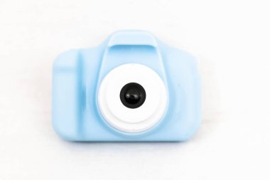 Mavi bir oyuncak, objektife odaklanarak beyaz arkaplanlı dijital kamerayı....