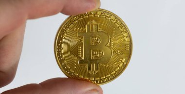 Beyaz arka planda altın Bitcoin 'i tutan parmakları kapat.