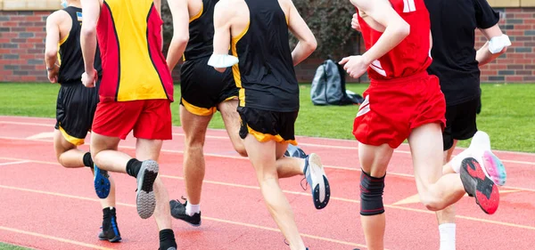 Yüzlerini maske takarak yarışan liseli çocukların açık hava pistinde yarıştıklarına dikkat edin..