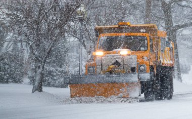 New York 'taki Long Island' da kar fırtınası sırasında kar yağarken, sarı bir belediye kar küreme aracı yolu açıyor..