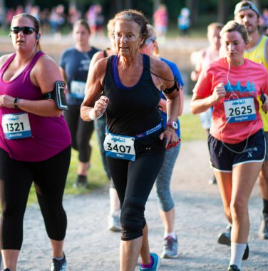 Kuzey Babylon, New York, ABD - 8 Temmuz 2019: Bir yaz akşamı Belmont gölünde koşan yaşlı ve genç koşucuların yakınları.
