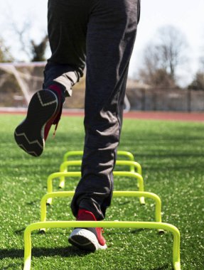 Düşük açılı bir erkek sporcunun tek bacağının üzerine atlaması yeşil bir çimenliğe arkadan fırlaması..