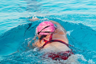 Triatlon antrenmanı yaparken duvardan itilen bir kadın yüzücünün arka görüntüsü..
