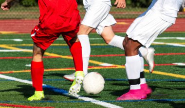 Close up of high school boys soccer players fighting for possession of the ball during a game on a turf field.