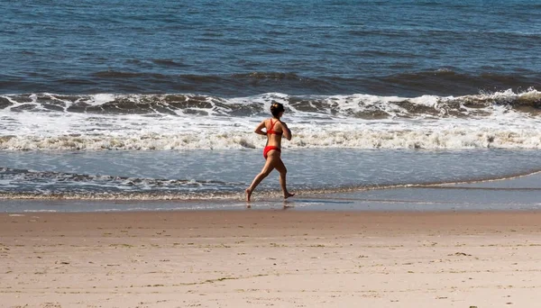 Achteraanzicht Van Een Vrouwelijke Badmeester Rode Bikini Lopend Het Oceaanwater — Stockfoto