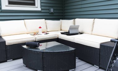 Bir arka bahçe güverte hasır koçu evden bilgisayar, telefon şişesi ve müzik hoparlörü ile çalışmak için kurulmuş..