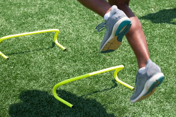 Atleta Masculino Saltando Sobre Mini Obstáculos Amarillos Campo Césped Verde —  Fotos de Stock