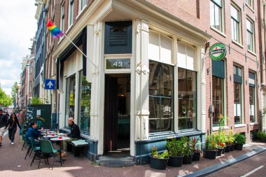 Amsterdam, Hollanda - 5 Ağustos 2025: Açık oturaklı, canlı çiçekli ve Amsterdam 'da renkli bayraklı açık kafe.