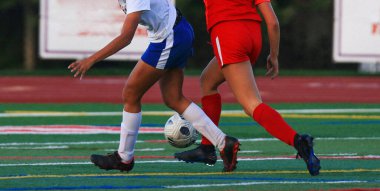 Canlı bir sahada topun peşinde koşan iki sporcuyu yakından takip edin..