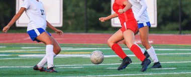 Üç sporcu canlı bir sahada rekabetçi bir futbol maçına katılıyor..