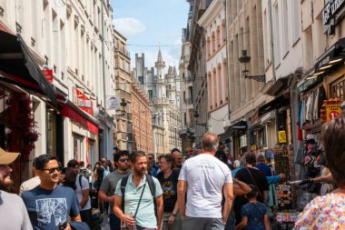 Brüksel, Belçika - 6 Ağustos 2025: Kalabalık dükkanlar ve tarihi binalarla dolu canlı bir caddeyi keşfediyor.