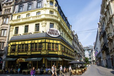 Brüksel, Belçika - 6 Ağustos 2025: Uyuşturucu Opera restoranının yakınında yürüyen ve dışarıda oturan insanlarla dolu bir cadde.