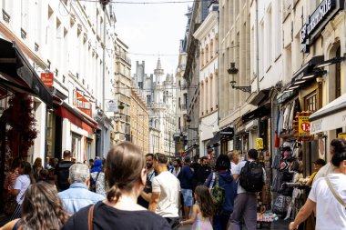 Brüksel, Belçika - 6 Ağustos 2025: Dar bir cadde boyunca gün boyunca dükkanları olan insanların.