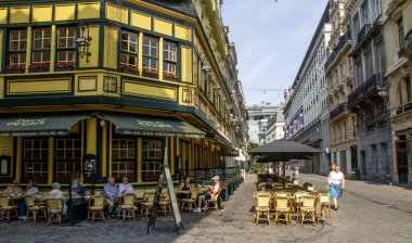 Brüksel, Belçika - 6 Ağustos 2025: İnsanlar yazın hareketli bir caddedeki büyüleyici bir kafede eğleniyorlar.