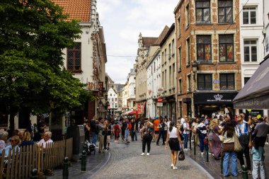 Brüksel, Belçika - 6 Ağustos 2025: Kalabalık büyüleyici bir kasabadaki dükkanlar ve kafelerle dolu canlı bir sokakta toplandı.