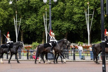 Londra, İngiltere - 7 Ağustos 2025: Kraliyet Muhafız Atlısı resmi kıyafetli insanlar parkın kenarından izliyorlar.