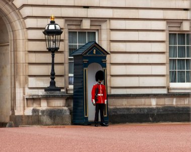 Londra, İngiltere - 7 Ağustos 2025: Bir muhafız açık gökyüzünün altındaki sarayın girişinde nöbet tutuyor.