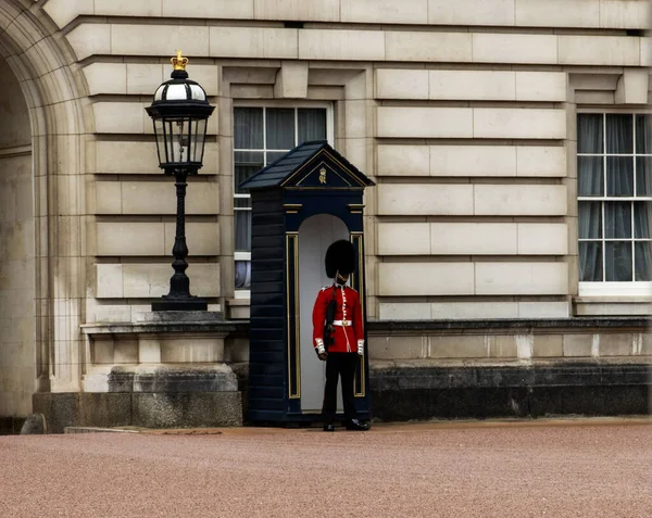 Londra, İngiltere - 7 Ağustos 2025: Bir muhafız açık gökyüzünün altındaki sarayın girişinde nöbet tutuyor.
