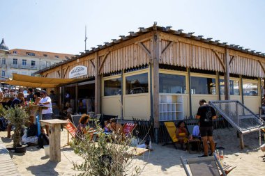 Soulac-sur-Mer, Fransa - 9 Ağustos 2025: Ziyaretçiler güneşli bir günde Soulac-sur-Mer 'de bir sahil kafede toplandılar.