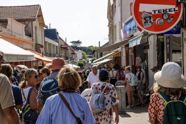 Soulac-sur-Mer, Fransa - 9 Ağustos 2025: Gün boyunca mağaza ve tezgahlarla dolu bir sokakta büyük bir kalabalık yürüyor.