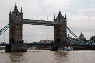 Londra, İngiltere - 7 Ağustos 2025: Londra 'da bir nehir üzerinden bir köprü geçiyor ve altında bir tekne suyun üzerinde hareket ediyor.