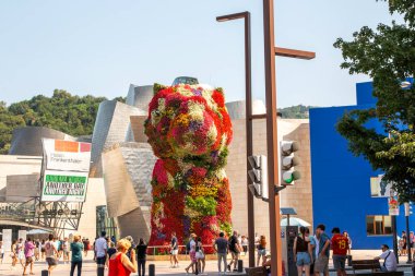 Bilbao, İspanya - 11 Ağustos 2025: İnsanlar sıcak bir günde Bilbao İspanya 'da büyük bir çiçek heykeline yürür ve hayran kalırlar.