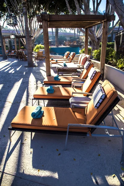 A row of orange lounge chairs by the edge of a swimming pool