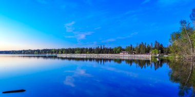 Gölün sakin suları boyunca uzanan uzun ağaçlar..