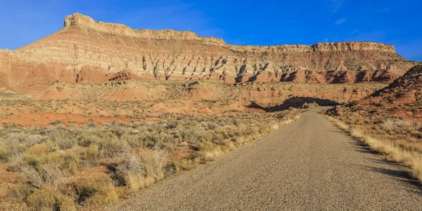 砂漠を通って舗装されていないグリッド道路は 距離で大きなメサにつながる — ストック写真