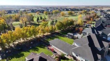 Sonbaharda Saskatoon yakınlarındaki Greenbryre 'in renkli ağaçları, lüks evleri ve 4K' daki golf sahalarını gösteren hava videosu..