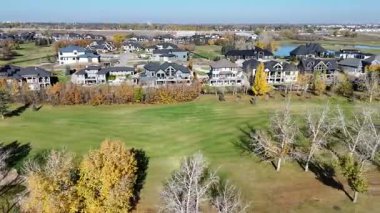 Sonbaharda Saskatoon yakınlarındaki Greenbryre 'in renkli ağaçları, lüks evleri ve 4K' daki golf sahalarını gösteren hava videosu..