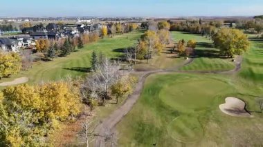 Sonbaharda Saskatoon yakınlarındaki Greenbryre 'in renkli ağaçları, lüks evleri ve 4K' daki golf sahalarını gösteren hava videosu..