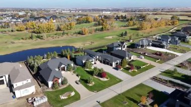 Sonbaharda Saskatoon yakınlarındaki Greenbryre 'in renkli ağaçları, lüks evleri ve 4K' daki golf sahalarını gösteren hava videosu..
