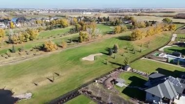 Sonbaharda Saskatoon yakınlarındaki Greenbryre 'in renkli ağaçları, lüks evleri ve 4K' daki golf sahalarını gösteren hava videosu..