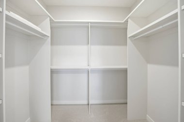 Beyaz duvarları ve rafları olan boş bir dolap. Dolap neredeyse çıplak, sadece birkaç şey görünüyor. Dolabın boşluğu huzur ve sadelik hissi veriyor.